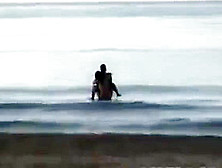 Couple Fools Around In The Water On A Public Beach